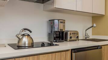 Eine moderne Küche mit Wasserkocher, Kaffeemaschine und Toaster auf der Arbeitsfläche, einem Spülbecken und Holzschränken.