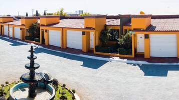 A row of yellow buildings with white garage doors, a central fountain, and a clear sky.