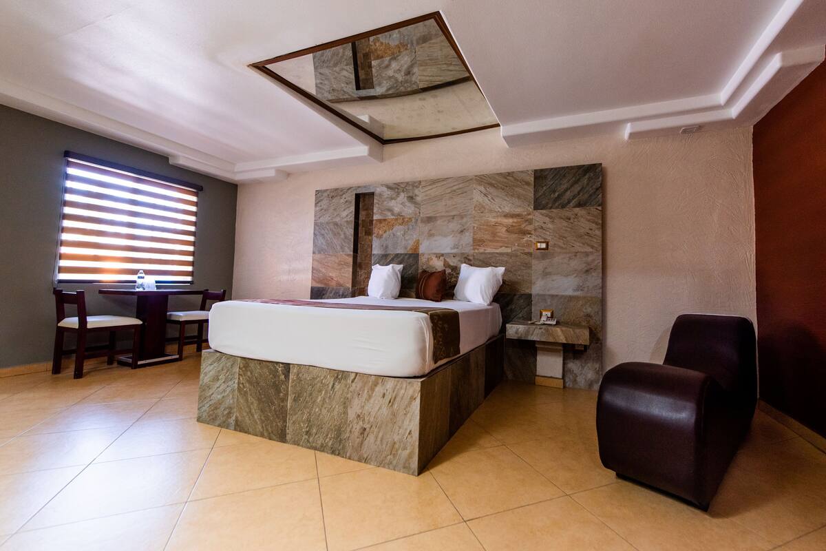 Una habitación de hotel con cama, escritorio, silla y una pared de piedra decorativa.