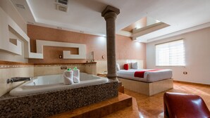 Ein modernes Hotelzimmer mit einer großen Badewanne, einem Bett mit roter Decke und einem Marmorboden.