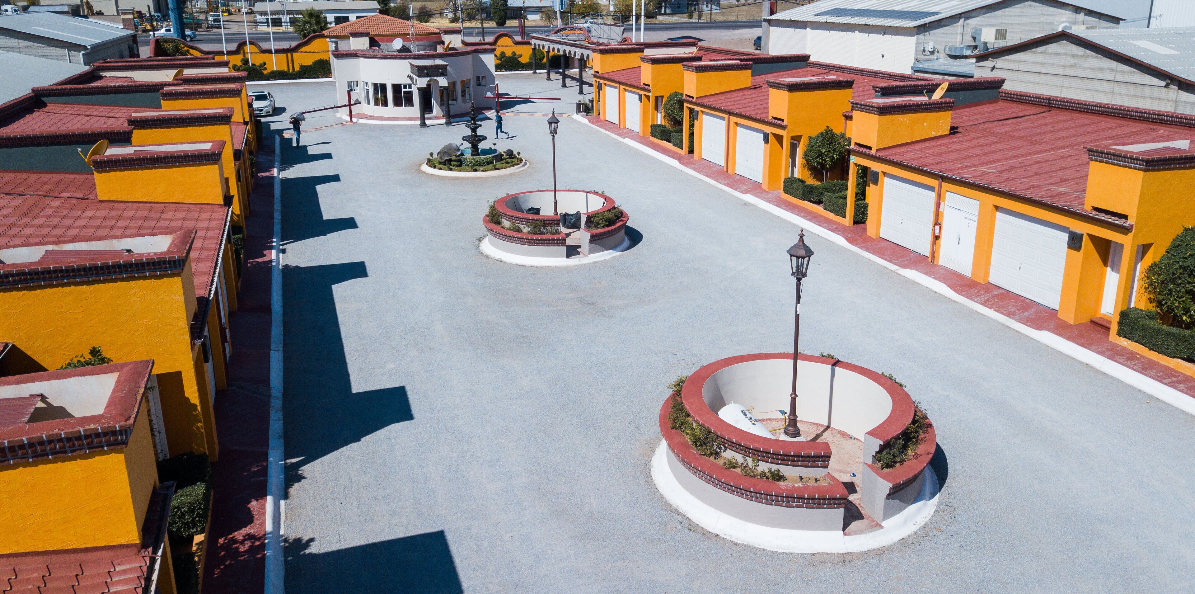 A courtyard with a fountain, surrounded by buildings with red-tiled roofs and yellow walls.