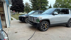 A parking area with two SUVs parked, one connected to a charging station. - Sundown Lodge in McMillan MI (McMillan)