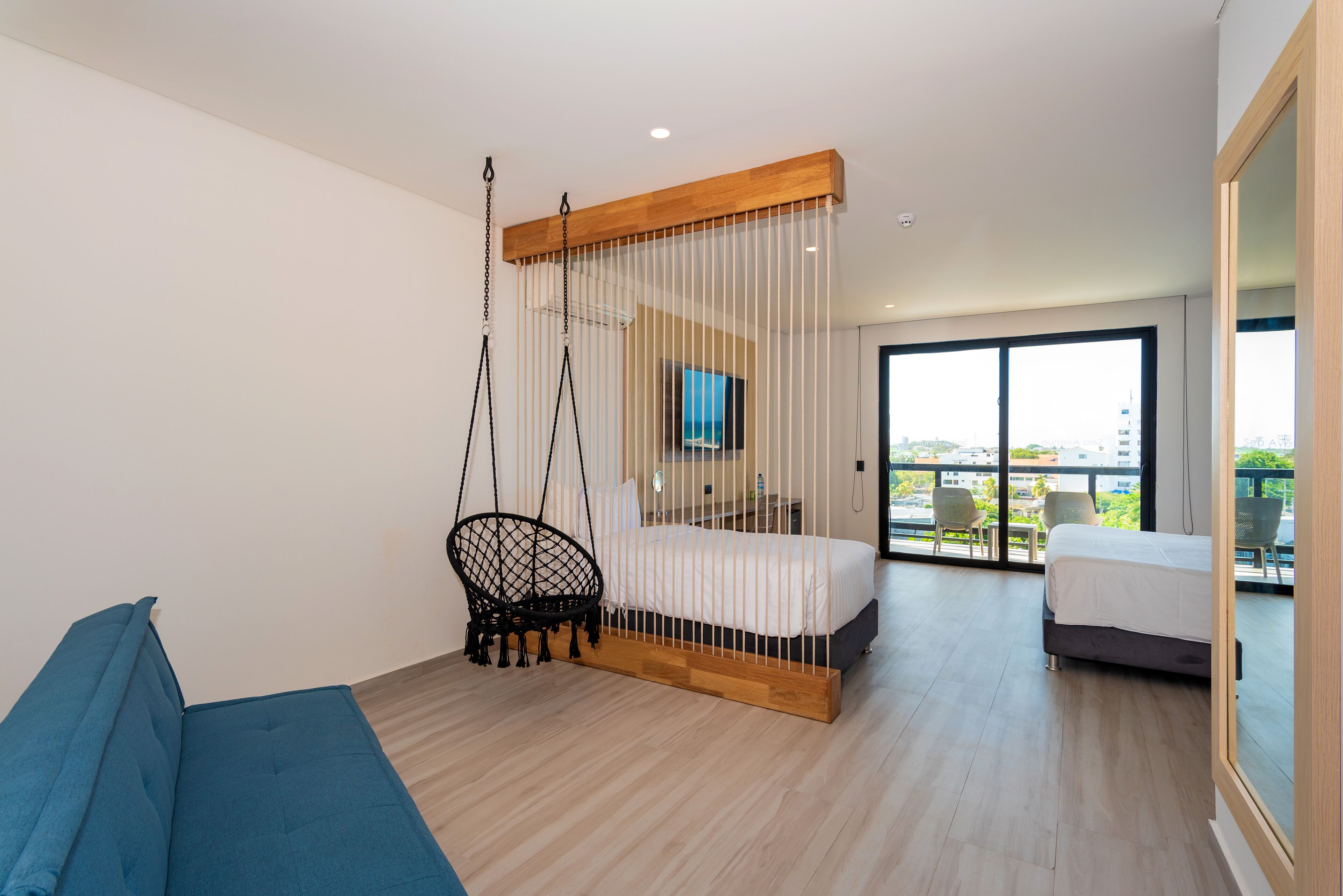 Un dormitorio moderno con una cama, un sillón colgante y un balcón con vistas.