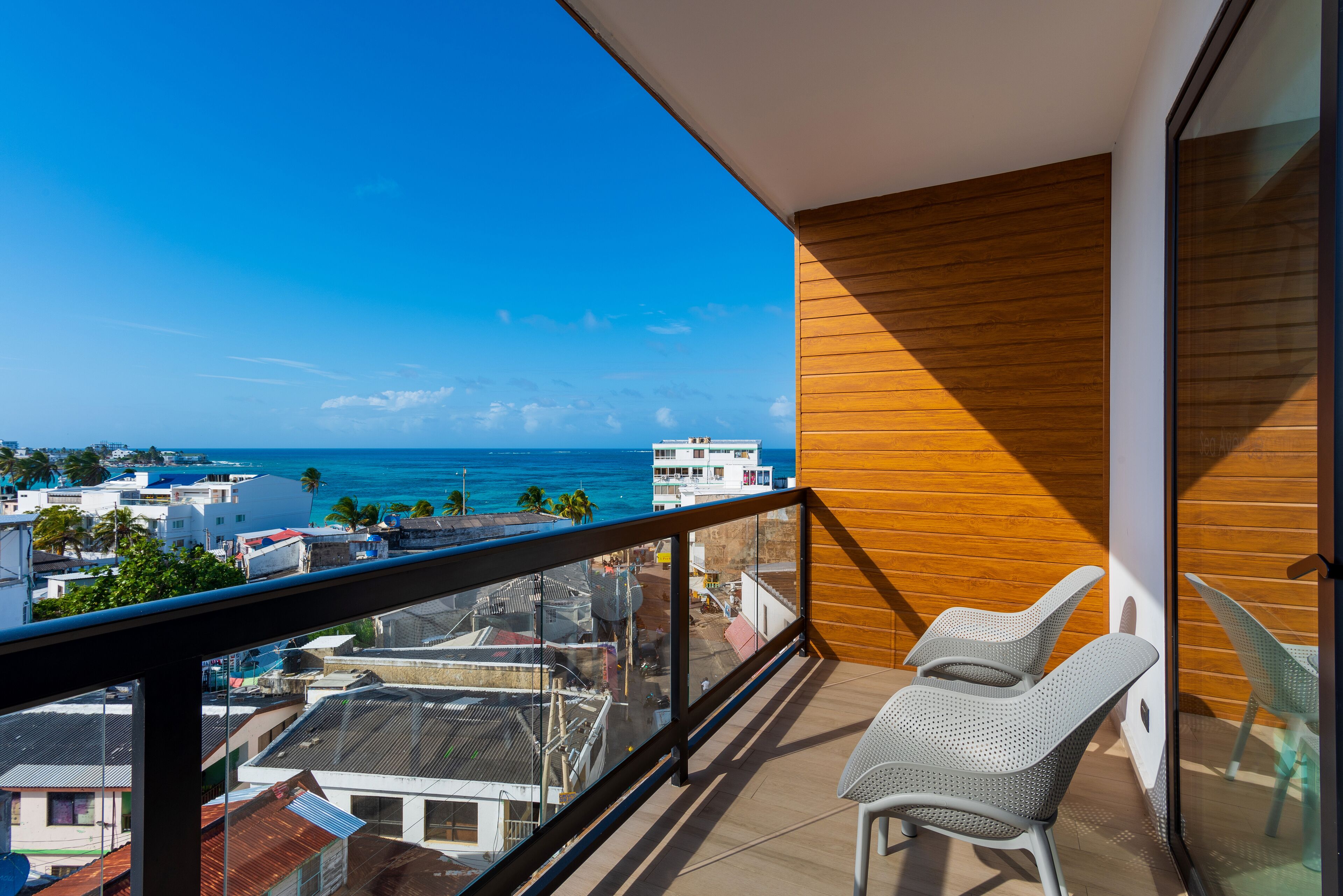 Un balcon avec vue sur l’océan et le paysage urbain.