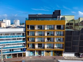 Un hotel de varios pisos con balcones, piscina y vista al mar.