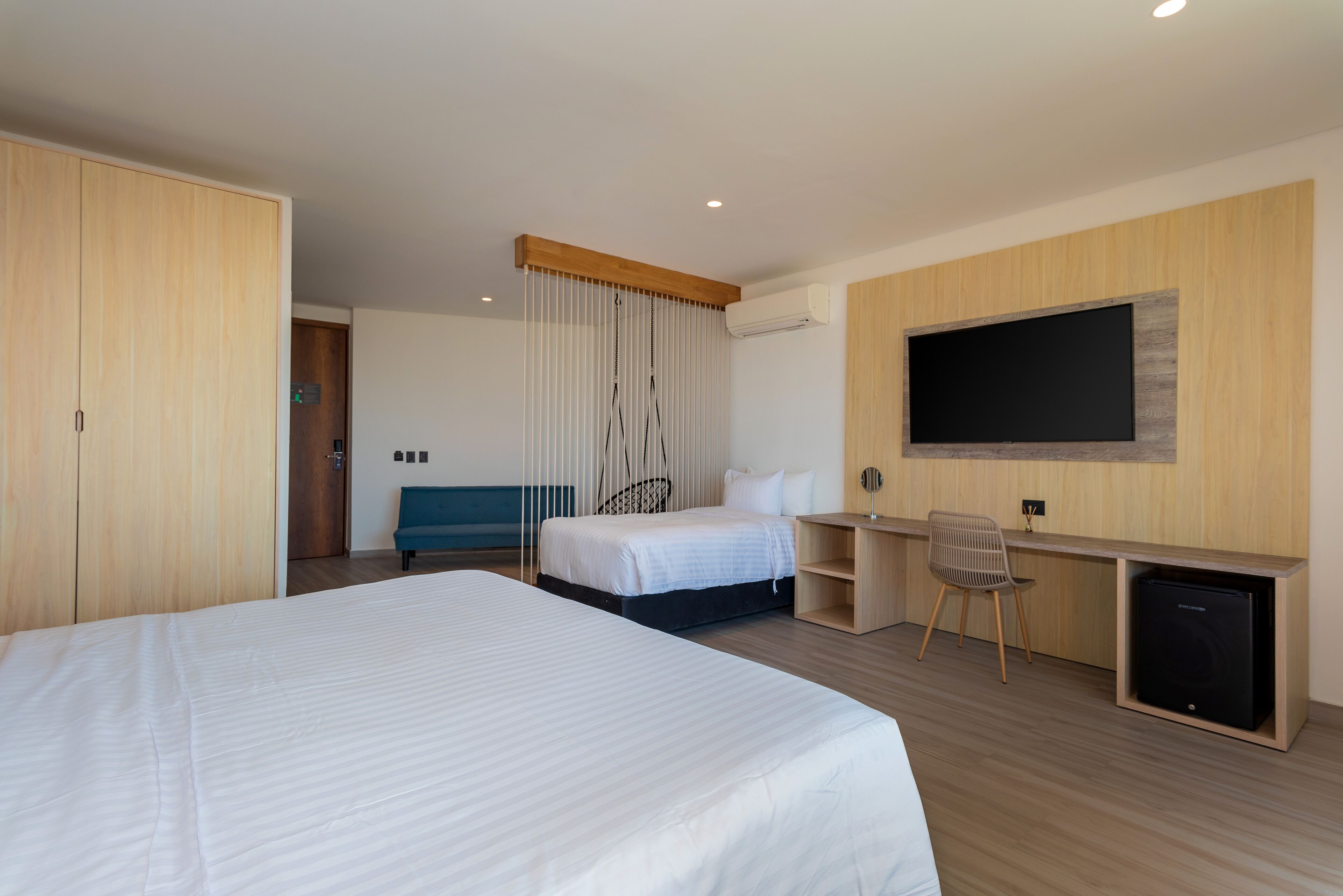 A hotel room with a large bed, a desk with a chair, a television, and a wardrobe.