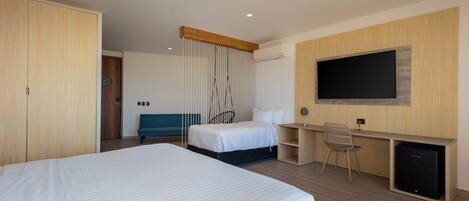 A hotel room with a large bed, a desk with a chair, a television, and a wardrobe.
