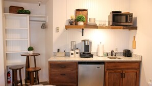 A compact kitchen with a dishwasher, coffee maker, microwave, and a small table with stools. - Cozy and Clean Park City Studio (Park City)