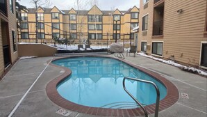 A swimming pool with a metal ladder, surrounded by a brick wall and a fence. - Cozy and Clean Park City Studio (Park City)