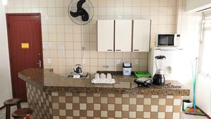 Eine Küche mit einer Granit-Arbeitsplatte, einem Wasserkocher, einem Ventilator, einer Mikrowelle, einem Mixer und einem Besen.