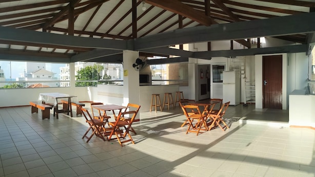 Eine geräumige Außenveranda mit Holztisch und -stühlen, einem Deckenventilator und Blick auf Gebäude im Hintergrund.