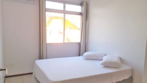 Ein kleines, sauberes Zimmer mit einem Einzelbett, einem Fenster und einer Tür.