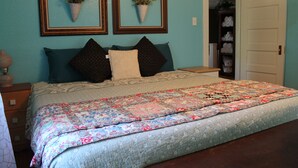 Une chambre à coucher comprenant un lit, une table de chevet, une commode et une porte donnant sur une autre pièce.