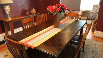 A dining table with a vase of flowers, wooden chairs, and a striped table runner.