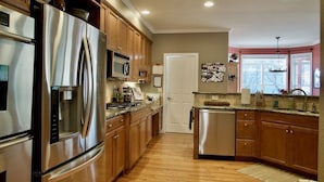 A modern kitchen with stainless steel appliances, wooden cabinets, and a central island.