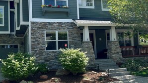 A two-story house with a stone facade, a red roof, and a front porch.