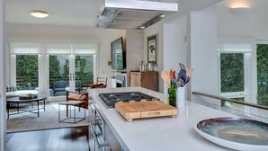 Una cocina moderna con una isla central, estufa y un ventanal grande.