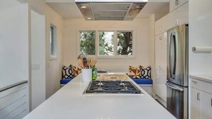 Una cocina moderna con una isla central, electrodomésticos de acero inoxidable y un ventanal que proporciona luz natural.