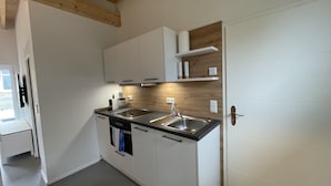 Una cocina moderna con armarios blancos, un lavamanos de acero inoxidable y vigas de madera en el techo.