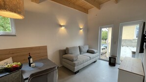 Una sala de estar moderna con un sofá, una mesa de comedor con un cuenco de fruta y un techo de madera.