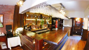 A bar area with a wooden counter, hanging glasses, and a brick wall. - Hotel Sonetto (Santiago)