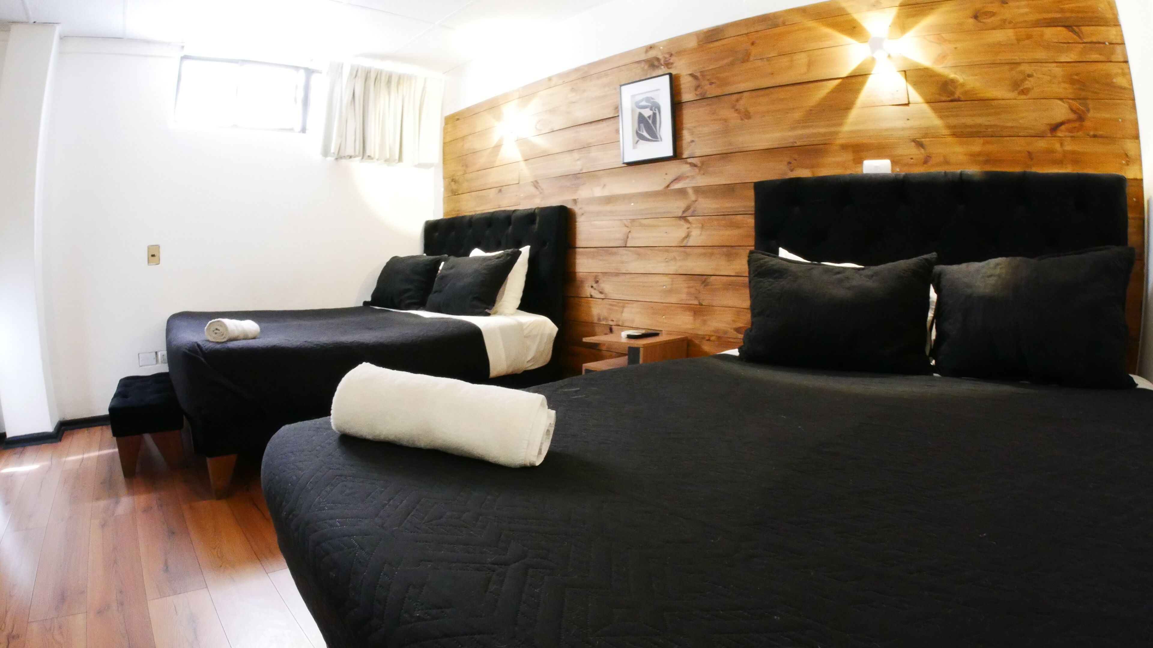 A hotel room with two beds, wooden paneling on the walls, a framed picture, and a small table.
