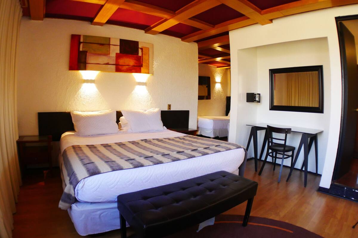 A hotel room with a large bed, bedside tables, a desk, and a chair.