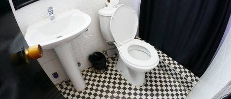 A bathroom with a sink, toilet, and checkered floor.