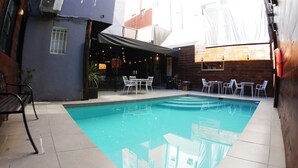 A pool area with a covered seating area, outdoor tables, and chairs. - Hotel Sonetto (Santiago)