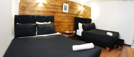A hotel room with two beds, a wooden headboard, a small bedside table, and a framed picture on the wall.