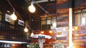 A rustic interior with wooden walls, hanging light bulbs, and a visible sign reading 'e Bella'. - Hotel Sonetto (Santiago)