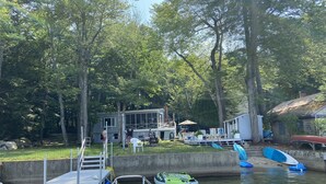 A dock with boats, a house, and a forested area.