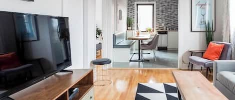 Una sala de estar moderna con un televisor de pantalla plana, una mesa de centro de madera y un tapete con estampado blanco y negro.