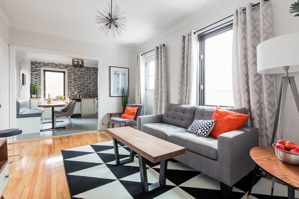 Una sala de estar moderna con un sofá gris, alfombra blanco y negro y una mesa de centro de madera.