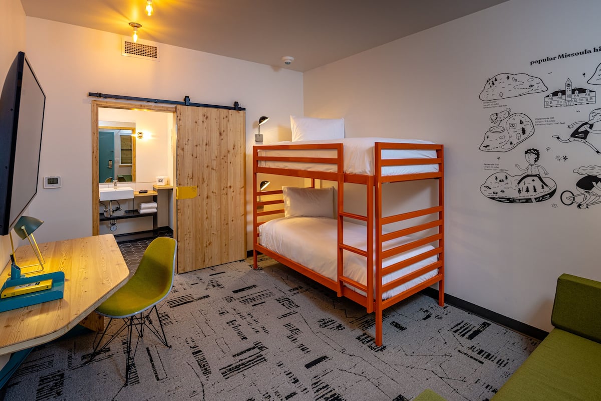 A bunk bed room with a desk, chair, and a mirror.