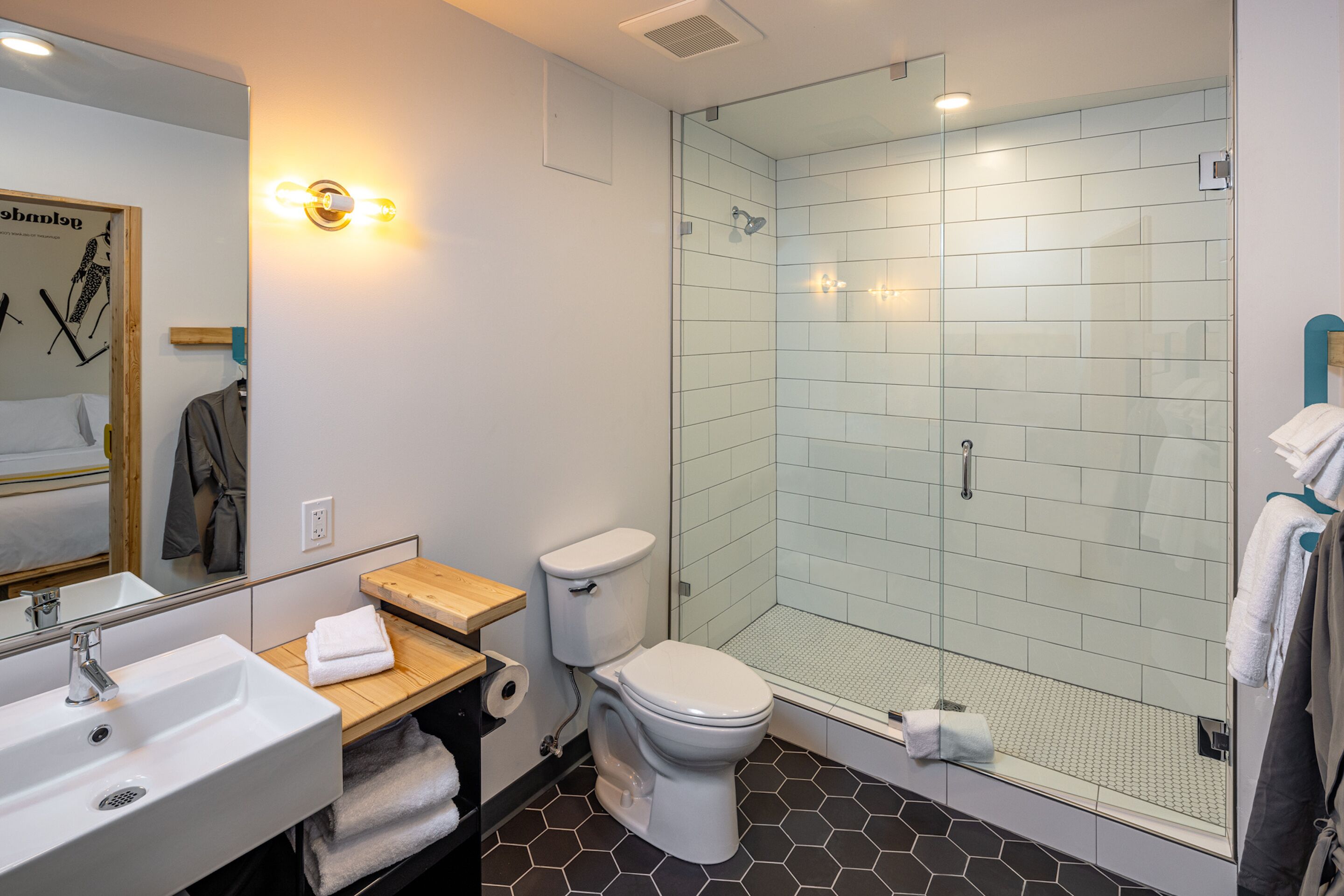 Un baño moderno con ducha envuelta en vidrio, un lavamanos blanco y un inodoro.