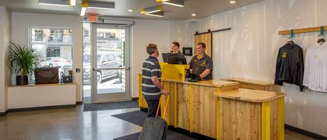 A reception area with a wooden counter, a potted plant, and a view of parked cars outside.