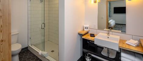 A modern bathroom with a glass-enclosed shower, a white sink, and a mirror with lights.