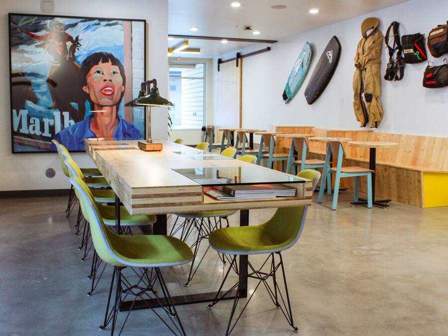 A conference room with a long table, green chairs, and a painting on the wall.