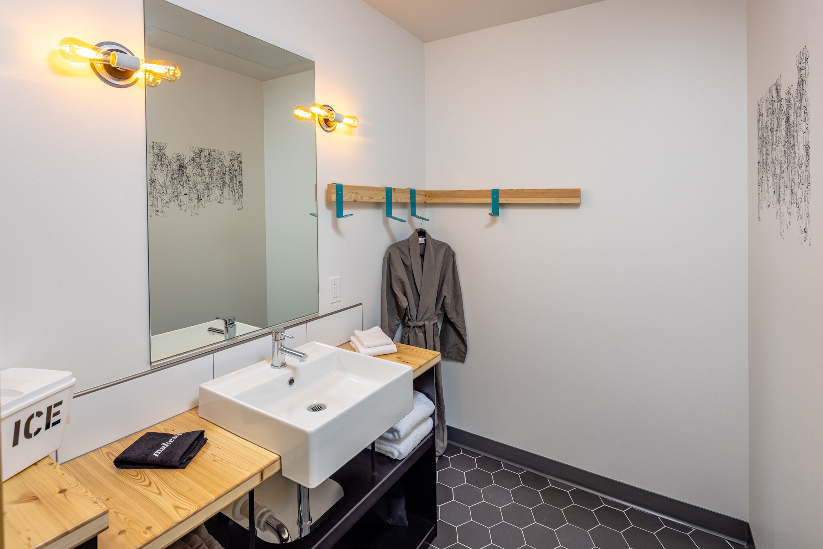 A modern bathroom with a large mirror, white sink, and wooden vanity.
