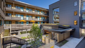 A modern multi-story building with balconies, outdoor seating, and a rooftop garden. - The Wren (Missoula)