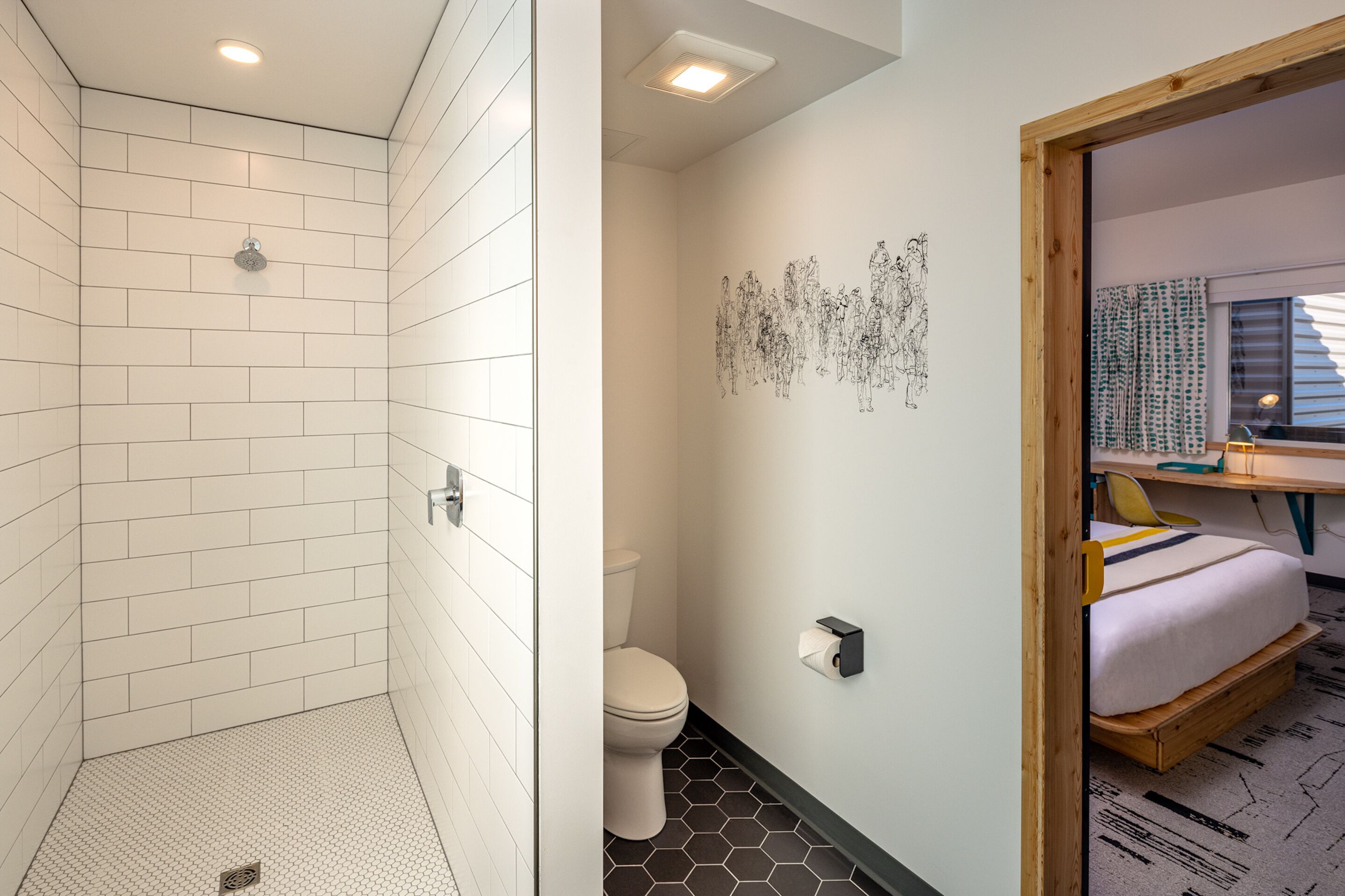 Een moderne badkamer met een douche, toilet en een bed in een aparte kamer.