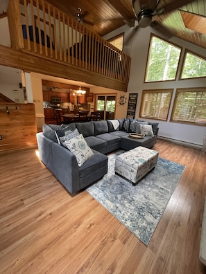Relax in this inviting living space with a large sofa and matching ottoman, surrounded by a beautiful area rug and a wooden staircase.