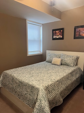 Ein Schlafzimmer mit einem Bett, einem Fenster und zwei gerahmten Bildern an der Wand.
