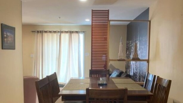 Un coin repas avec une table et des chaises, un canapé, une fenêtre avec des rideaux et un tableau au mur.