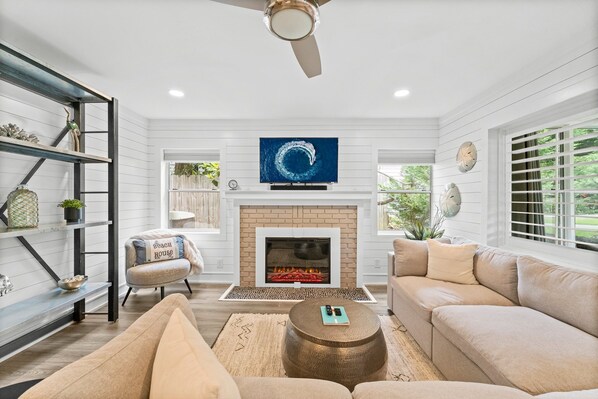 A living room with a fireplace, a sofa, a coffee table, and a TV mounted above the fireplace. - Classic Seagrove Cottage One Block from 30A Beach Access (Santa Rosa Beach)