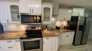 Une cuisine moderne avec des meubles blancs, des appareils en acier inoxydable et des plans de travail en granit.