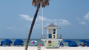 Une tour de surveillance avec le numéro 3, des parasols et des chaises longues sur une plage de sable.