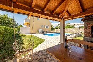 A wooden pergola with a hanging swing, a stone patio, a pool, and a brick oven. - Villa Basil Zadarvillas (Benkovac)