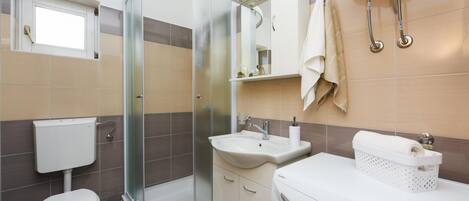 Une salle de bain moderne avec une douche à parois de verre, des toilettes, un lavabo et un lave-linge.